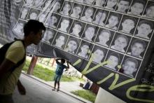 A child stands underneath a banner showing the photographs of the 43 missing students of the Ayotzinapa teachers' training college, at the college in Tixtla, on the outskirts oft Chilpancingo, in the Mexican state of Guerrero, August 15, 2015. PHOTO BY REUTERS/Jorge Dan Lopez