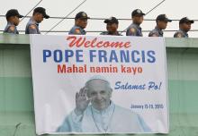 Members of the Philippine National Police walk past a banner with an image of Pope Francis as they go to their designated area in Manila, January 15, 2015. PHOTO BY REUTERS/ Cheryl Ravelo