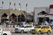 People stand amidst debris near a Turkish restaurant following a gas explosion in Doha
