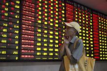 An investor looks at an electronic board showing stock information at a brokerage house in Nanjing, Jiangsu province, China, July 24, 2015. PHOTO BY REUTERS/China Daily