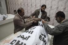 A man (2nd L) mourns over the covered body of his brother who was among four workers of an anti-polio drive campaign shot by gunmen, at a hospital morgue in Quetta, November 26, 2014. PHOTO BY  REUTERS/Naseer Ahmed