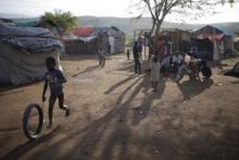 A boy plays with a tire as others fix a motorcycle at a refugee camp for Haitians returning from the Dominican Republic on the outskirts of Anse-a-Pitres, Haiti, September 7, 2015. PHOTO BY REUTERS/Andres Martinez Casares