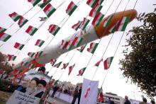 A boy holding a placard with pictures of (L-R) President Hassan Rouhani, the late founder of the Islamic Revolution Ayatollah Ruhollah Khomeini, and Iran's Supreme Leader Ayatollah Ali Khamenei, poses for camera in front of a model of Simorgh satellite-carrier rocket during a ceremony marking the 37th anniversary of the Islamic Revolution, in Tehran February 11, 2016. PHOTO BY REUTERS/Raheb Homavandi
