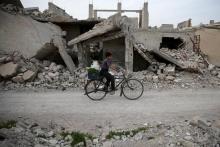 A boy rides a bicycle near rubble of damaged buildings in the rebel held besieged town of Douma, eastern Damascus suburb of Ghouta, Syria, March 19, 2016. PHOTO BY REUTERS/Bassam Khabieh