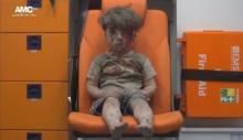 A still image taken on August 18, 2016 from a video posted on social media said to be shot in Aleppo on August 17, 2016, shows a boy with bloodied face sitting in an ambulance, after an airstrike, Syria. PHOTO BY REUTERS/Social Media