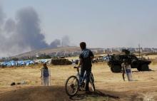A Turkish Kurdish boy stands near the Mursitpinar border gate in Suruc in Sanliurfa province, Turkey, as smoke rises in the Syrian town of Kobani in the background, June 27, 2015. PHOTO BY REUTERS/Murad Sezer