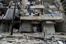 Boys stand amid the damage in the government-held al-Shaar neighborhood of Aleppo, during a media tour, Syria, December 13, 2016. PHOTO BY REUTERS/Omar Sanadiki
