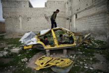 Boys play on a wrecked car in the rebel held besieged Douma neighbourhood of Damascus, Syria, April 1, 2017. PHOTO BY REUTERS/Bassam Khabieh
