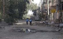 Boys ride bicycles past damaged buildings along a deserted street in Deir al-Zor, eastern Syria, March 7, 2014. PHOTO BY REUTERS/Mohamed al-Khalif