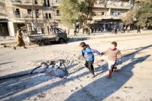 Boys run near a hole in the ground after airstrikes by pro-Syrian government forces in the rebel held al-Sakhour neighborhood of Aleppo, Syria, February 8, 2016. PHOTO BY REUTERS/Abdalrhman Ismail