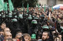 People watch as Palestinian members of al-Qassam Brigades, the armed wing of the Hamas movement, take part in a military parade marking the 27th anniversary of Hamas' founding, in Gaza City, December 14, 2014. PHOTO BY REUTERS/Mohammed Salem