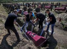 Workers take part in a mass funeral ceremony to bury 57 unidentified members of Ukrainian military forces who were killed in the conflict in eastern regions, in the settlement of Kushuhum near Zaporizhia, Ukraine, August 7, 2015. PHOTO BY REUTERS/Gleb Garanich