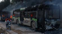 A man on a motorcycle drives past burning buses while en route to evacuate ill and injured people from the besieged Syrian villages of al-Foua and Kefraya, after they were attacked and burned, in Idlib province, Syria, December 18, 2016. PHOTO BY REUTERS/Ammar Abdullah