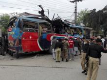 Policemen and rescue officials walk near a bus damaged in a bomb blast in Peshawar, Pakistan, March 16, 2016. PHOTO BY REUTERS/Fayaz Aziz