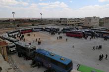People, who were evacuated from the two rebel-besieged Shi'ite villages of al-Foua and Kefraya, stand near buses at insurgent-held al-Rashideen, Aleppo province, Syria, April 19, 2017. PHOTO BY REUTERS/Ammar Abdullah