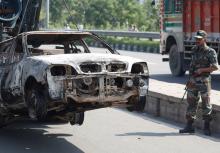 A soldier looks at a burnt out car after a day of violence in Panchkula, India, August 26, 2017. PHOTO BY REUTERS/Cathal McNaughton