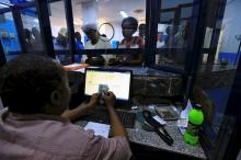 A cashier counts US Dollars as people wait to receive money inside Bab Al-Mandab Exchange transfer money bureau in Khartoum, Sudan, October 7, 2017. PHOTO BY REUTERS/Mohamed Nureldin Abdallah