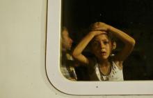 A migrant child looks out of a train window at a train station in Tovarnik, September 19, 2015. PHOTO BY REUTERS/Antonio Bronic
