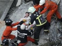 Rescue personnel help a child rescued at the site where a 17-storey apartment building collapsed during an earthquake in Tainan, southern Taiwan, February 6, 2016. PHOTO BY REUTERS/Stringer