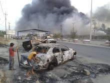 Children stand next to a burnt vehicle during clashes between Iraqi security forces and al Qaeda-linked Islamic State in Iraq and the Levant (ISIL) in the northern Iraq city of Mosul