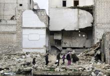 Children walk on the debris of a damaged building at al-Myassar neighborhood of Aleppo, February 16, 2015. PHOTO BY REUTERS/Hosam Katan