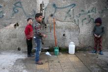 Children fill containers with water in the rebel held besieged town of Douma, eastern Damascus suburb of Ghouta, Syria, March 19, 2016. PHOTO BY REUTERS/Bassam Khabieh