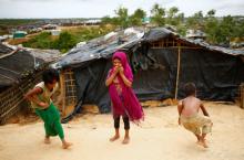 A Rohingya refugee girl reacts to the camera while two other children busy to play marble at the Kutupalang Makeshift Refugee Camp in Cox's Bazar, Bangladesh, July 8, 2017. PHOTO BY REUTERS/Mohammad Ponir Hossain