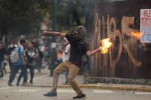 A demonstrator throws a molotov cocktail during clashes with riot police while rallying against Venezuela's President Nicolas Maduro in Caracas. PHOTO BY REUTERS/Christian Veron