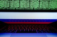 A Russian flag is seen on a laptop screen in front of a computer screen displaying cyber code. REUTERS/Kacper Pempel/Illustration