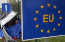 An EU sign is seen as a migrant rests at the border crossing from Slovenia in Trnovec, Croatia, October 19, 2015. PHOTO BY REUTERS/Antonio Bronic