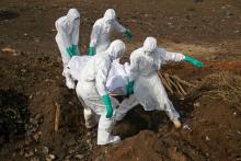 Health workers carry the body of a suspected Ebola victim for burial at a cemetery in Freetown, Sierra Leone, December 21, 2014. PHOTO BY REUTERS/Baz Ratner
