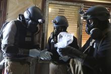 A U.N. chemical weapons expert, wearing a gas mask, holds a plastic bag containing samples from one of the sites of an alleged chemical weapons attack in the Ain Tarma neighbourhood of Damascus