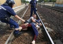 Hungarian policemen stand by the family of migrants as they wanted to run away at the railway station in the town of Bicske, Hungary, September 3, 2015. PHOTO BY REUTERS/Laszlo Balogh