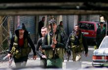 Members of the Palestinian Fatah faction walk with their weapons as seen through a damaged car inside the Ain el-Hilweh refugee camp near Sidon, southern Lebanon, April 11, 2017. PHOTO BY REUTERS/Ali Hashisho
