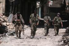 Syria Democratic Forces (SDF) fighters walk on the rubble of damaged shops and buildings in the city of Manbij, in Aleppo Governorate, Syria, August 10, 2016. PHOTO BY REUTERS/Rodi Said