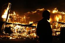 A man watches a burning building after a grand jury returned no indictment in the shooting of Michael Brown in Ferguson, Missouri, November 24, 2014. PHOTO BY REUTERS/Jim Young