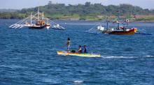 Fishermen ride on a small boat past their big boats as they prepare to fish at disputed Scarborough Shoal, at the coastal village of Cato in Infanta, Pangasinan in the Philippines, November 3, 2016. PHOTO BY REUTERS/Erik De Castro