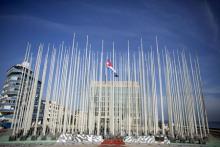 A Cuban flag flies in front of the U.S. Interests Section (background) in Havana, July 19, 2015. PHOTO BY REUTERS/Alexandre Meneghini