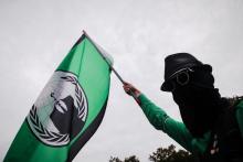 A man holds a flag of the Anonymous hacker group during a "Freiheit Statt Angst" (Freedom instead of Fear) protest calling for the protection of digital data privacy and the reigning in of digital surveillance practices, in Berlin