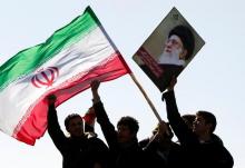 Demonstrators wave Iran's flag and hold up a picture of supreme leader Ayatollah Ali Khamenei during a ceremony to mark the 33rd anniversary of the Islamic Revolution, in Tehran's Anadi square, February 11, 2012. PHOTO BY REUTERS/Raheb Homavandi