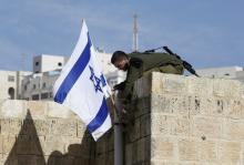 An Israeli soldier removes the Israeli flag from a house as Israeli troops forcibly remove Jewish settlers from homes, in the West Bank city of Hebron, January 22, 2016. PHOTO BY REUTERS/Mussa Qawasma
