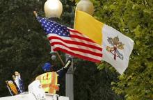 A worker places U.S. and Vatican flags together on a lamp post along Pennsylvania Avenue in front of the White House in Washington, September 21, 2015. PHOTO BY REUTERS/Kevin Lamarque