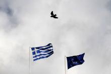 A Greek (L) and an EU flag flutter as a pigeon flies past in Athens, January 6, 2015. PHOTO BY REUTERS/Alkis Konstantinidis
