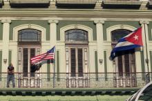 A man stands near the national flags of the U.S. and Cuba (R) on the balcony of a hotel being used by the first U.S. congressional delegation to Cuba since the change of policy announced by U.S. President Barack Obama on December 17, in Havana, January 19, 2015. PHOTO BY REUTERS/Stringer