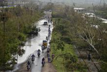 Vehicles move through a flooded road next to the trees fallen over railway tracks after being damaged by strong winds caused by the Cyclone Hudhud in the southern Indian city of Visakhapatnam