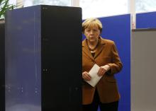 German Chancellor and leader of Christian Democratic Union (CDU) Angela Merkel fills-in her ballot paper before casting her vote