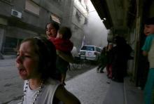 Ghazal, 4, (L) and Judy, 7, carrying 8-month-old Suhair, react after what activists said was shelling by forces loyal to Syria's President Bashar al-Assad near the Syrian Arab Red Crescent center in the Douma neighborhood of Damascus, May 6, 2015. PHOTO BY REUTERS/Bassam Khabieh
