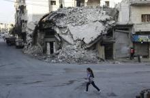 A girl runs past damaged buildings in the rebel-controlled area of Maaret al-Numan town in Idlib province, Syria, December 21, 2015. PHOTO BY REUTERS/Khalil Ashawi