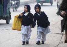Girls carry their school bags as they walk along a road while heading to their school after it reopened in Peshawar, January 12, 2015. PHOTO BY REUTERS/Khuram Parvez