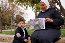 Hajar Saleh poses with her grandson Jaafar as she holds a picture depicting Jaafar's parents, Amina Saleh and her husband Imad Azouz who were killed fleeing Syria's civil war, at a garden in the Damascus district of Mezzeh, Syria, March 30, 2017. PHOTO BY REUTERS/Omar Sanadiki